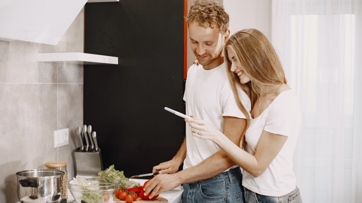 Couple happily preparing a healthy meal together in a modern kitchen setting.